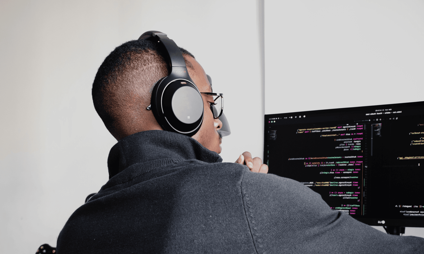 Picture of a software engineer coding in a computer using an external monitor